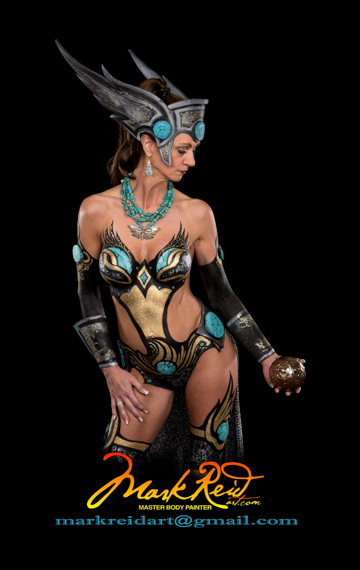 Woman with a body painting resembling a Valkyre theme gazing into a brass globe in her hand